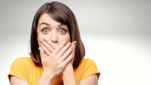 Woman looking surprised holding her hands over her mouth