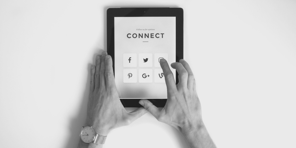 Hands hold tablet with social media icons and the word 'connect'
