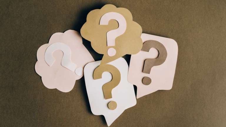 Paper cutouts of speech bubbles with question makrs on them