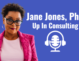 A graphic for featured interview on The Social Academic. Blue background with white text reads that the interview is with Jane Jones, PhD of Up In Consulting. There is an icon of headphones on a microphone to represent podcasting. A cutout photo of Jane, a black woman, is on the graphic. She is wearing a bright pink lace blazer over a light pink top, hoop earrings, and glasses. Jane is smiling and looking at the camera.