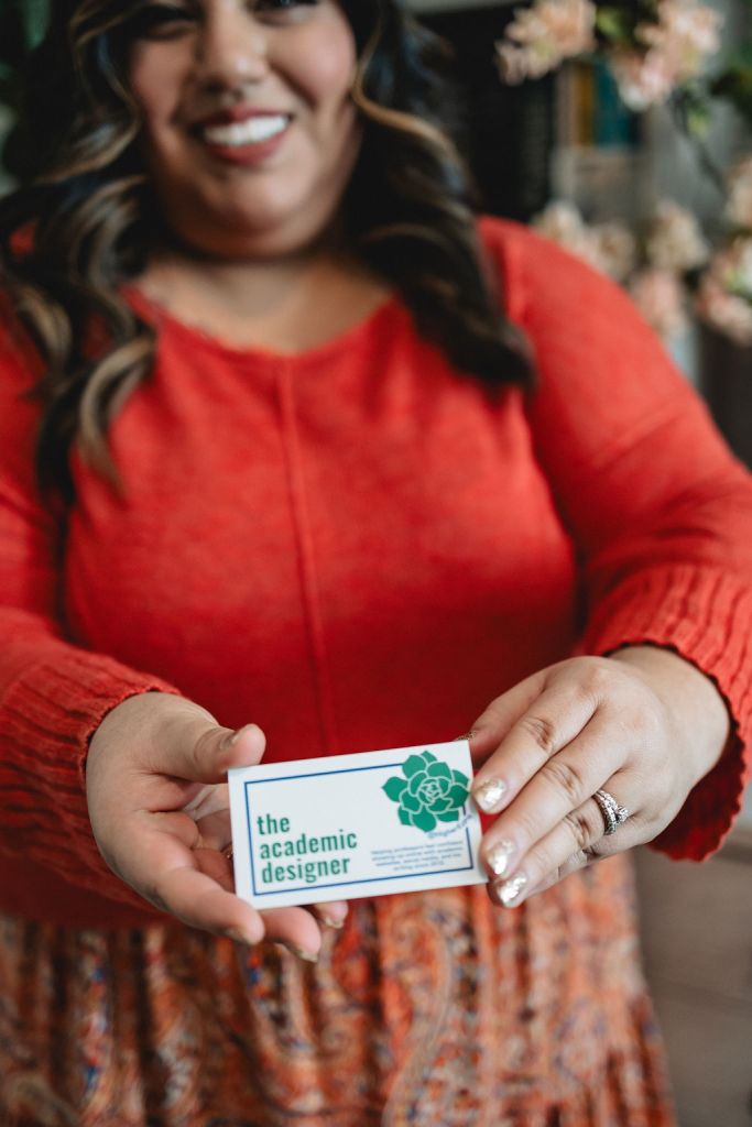 Jennifer van Alstyne holding a business card for The Academic Designer LLC