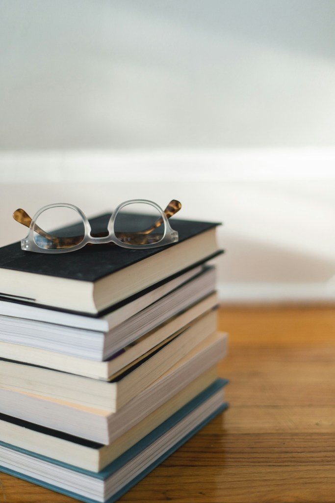 Stack of books with a pair of glasses folded on top