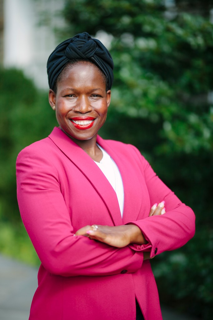 Dr. Tiffany Green, a black woman professor, wears a dark pink blazer. She's smiles with her arms lightly crossed.