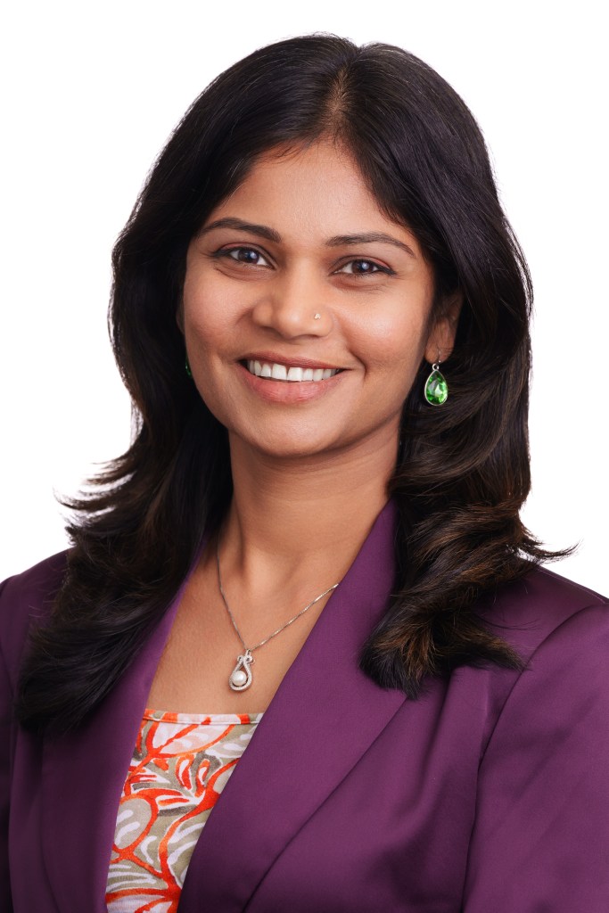Aksthata Naik, PhD smiles. She's wearing a plum blazer and a patterned top.